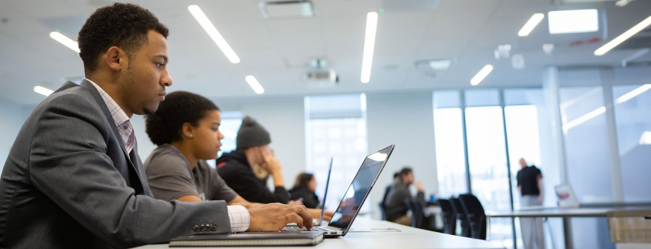 Three students sit at a table working during a classroom session
